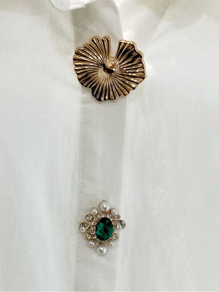 Camisa com mangas bufantes e botões cravejados de joias.