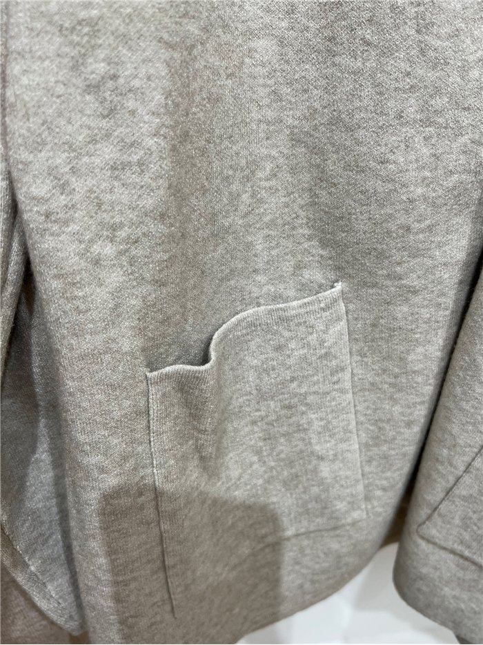 Jaqueta de tricô oversized com capuz e bolsos frontais.